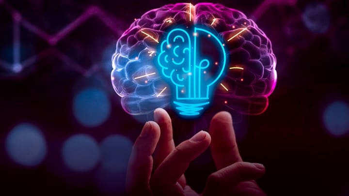 A person holding their hands up to the light bulb in front of a glowing brain.