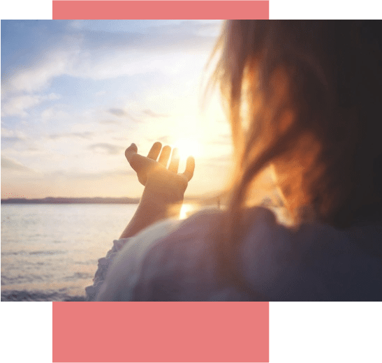 A woman sitting on top of her head with the sun setting in the background.