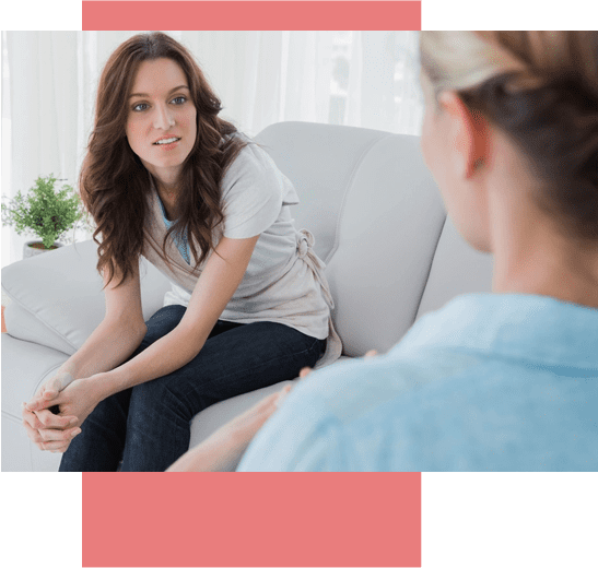 A woman sitting on the couch talking to another person.